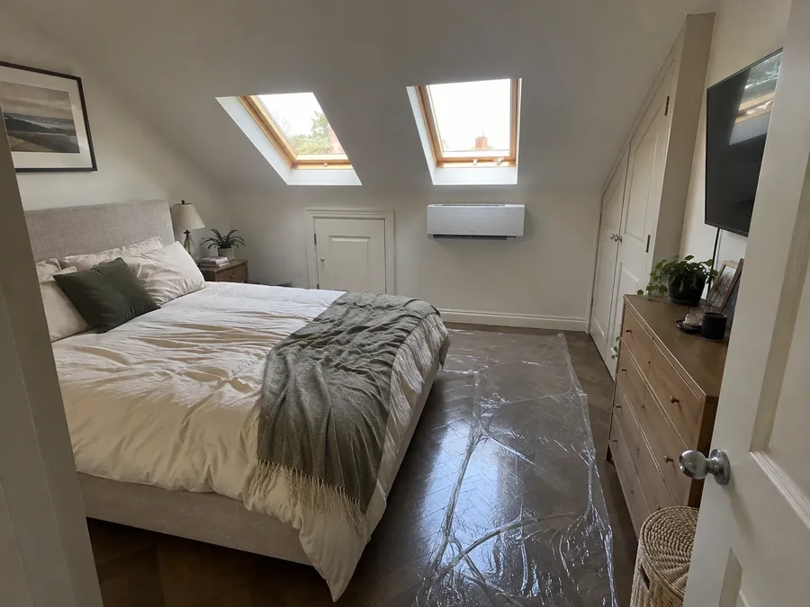 Loft bedroom under two skylights, wall unit fitted beside the doorway and the floor still sheeted