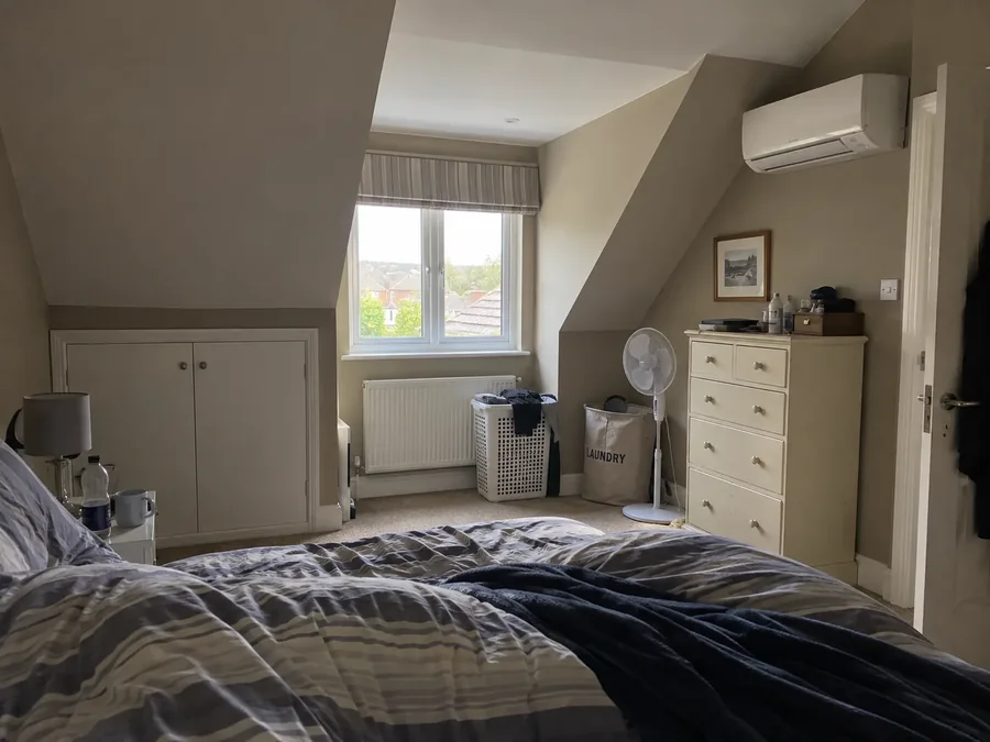 Attic bedroom under a sloping ceiling with the air conditioning fitted