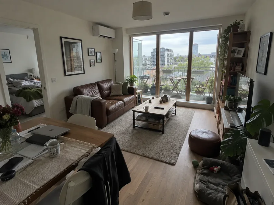 Open-plan flat living and dining space, unit high on the wall beside the balcony doors