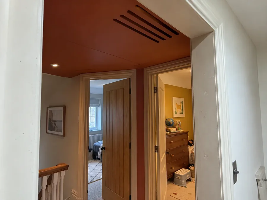 Landing ceiling with a slim linear grille where the pipework runs