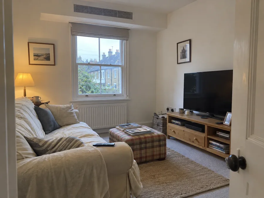 Sitting room with a slim grille high on the wall above the window
