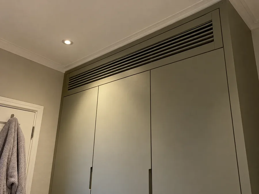 Close-up of a grille let into the sloping top of a fitted wardrobe