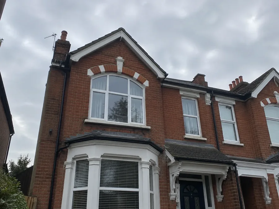 Red-brick Victorian semi-detached house with bay windows and a gabled roof