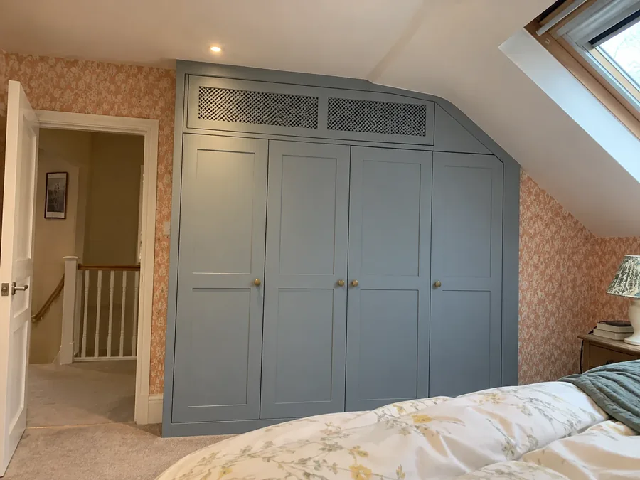 Fitted bedroom wardrobes with a ventilation grille set into the cabinetry above the doors, the unit hidden behind it