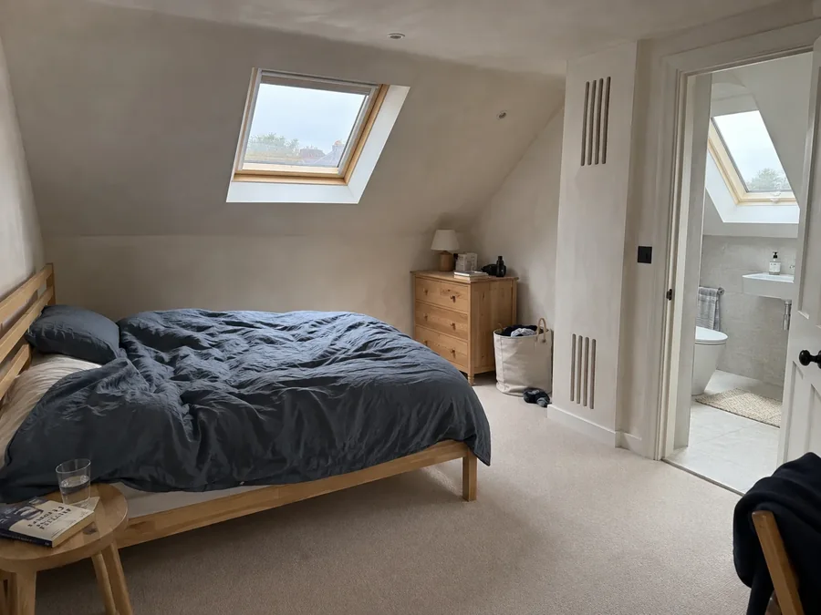 Attic bedroom with two slim vertical grilles in the wall beside the door