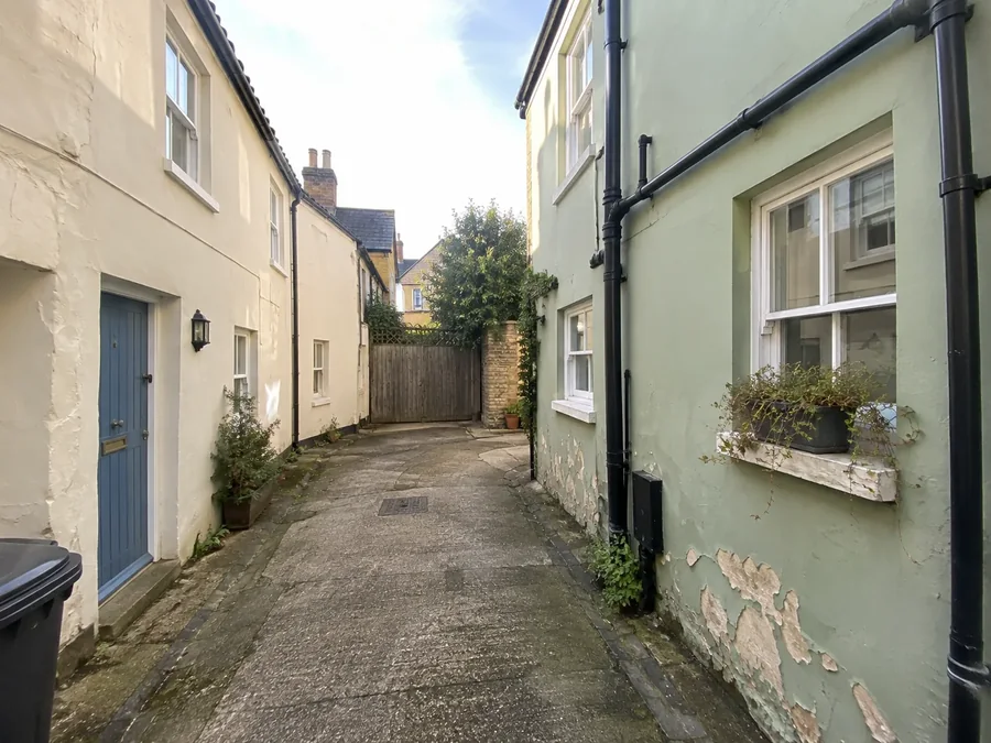 Narrow mews lane between painted cottages