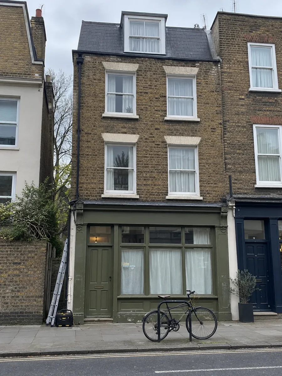 Narrow four-storey townhouse on a London street with a shopfront at ground level